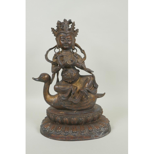 133 - A Tibetan gilt and coppered bronze figure of Guan Yin riding a duck, double vajra mark to base, 29cm... 