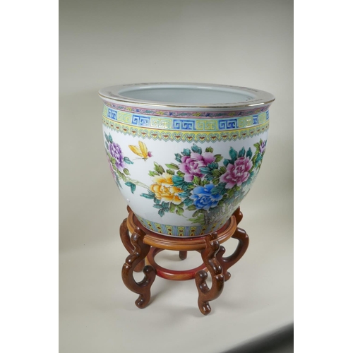 136 - A Chinese famille rose porcelain fish bowl on a wood stand, decorated with butterflies and flowers, ... 