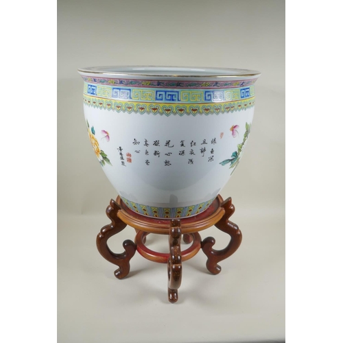 136 - A Chinese famille rose porcelain fish bowl on a wood stand, decorated with butterflies and flowers, ... 