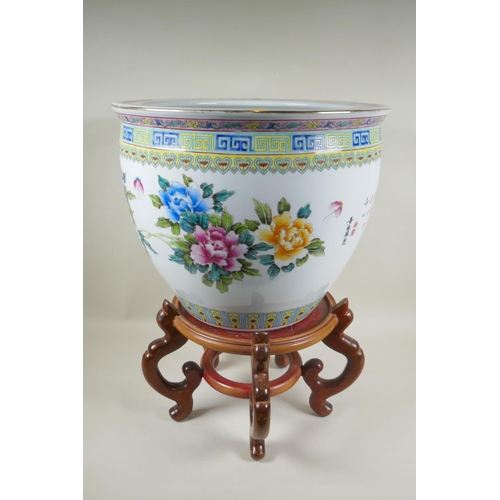 136 - A Chinese famille rose porcelain fish bowl on a wood stand, decorated with butterflies and flowers, ... 