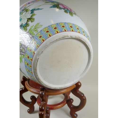 136 - A Chinese famille rose porcelain fish bowl on a wood stand, decorated with butterflies and flowers, ... 