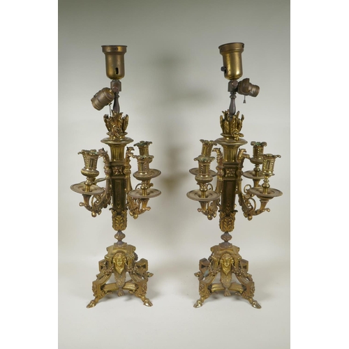 217 - A pair of gilt bronze four branch candelabra, decorated with swags, masks and arrow fletchings, the ... 