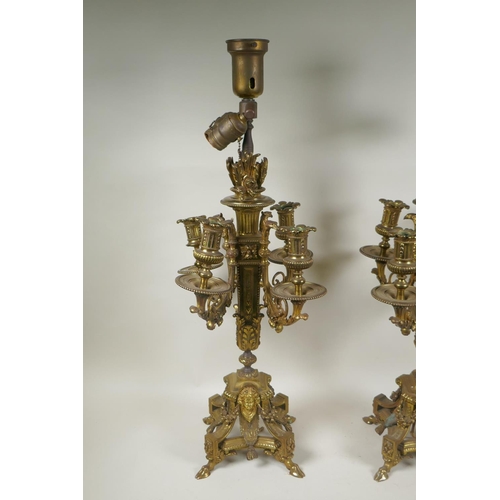 217 - A pair of gilt bronze four branch candelabra, decorated with swags, masks and arrow fletchings, the ... 