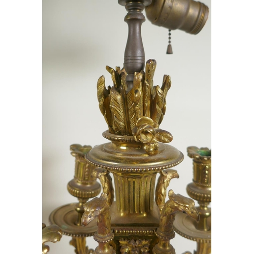 217 - A pair of gilt bronze four branch candelabra, decorated with swags, masks and arrow fletchings, the ... 