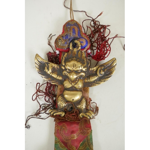 59 - A Tibetan bronze Garuda amulet on a silk mount, and a bronze carp shaped padlock, 23cm long