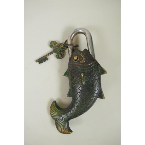 59 - A Tibetan bronze Garuda amulet on a silk mount, and a bronze carp shaped padlock, 23cm long