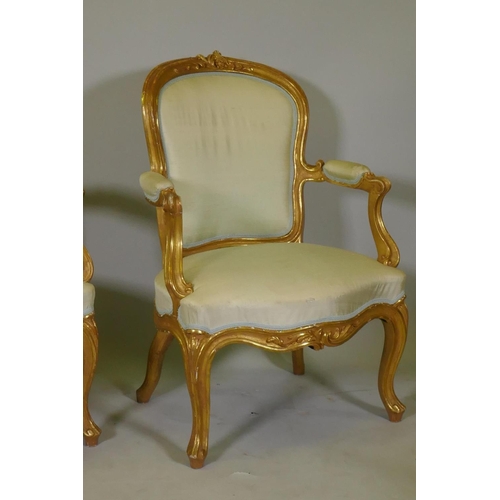 1001 - A pair of antique watergilt show frame armchairs with carved decoration and silk covers, raised on c... 