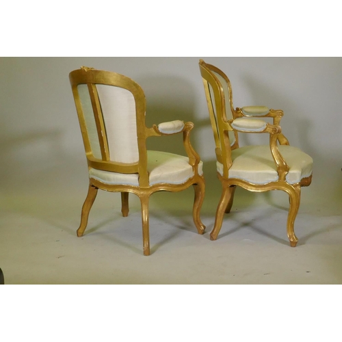 1001 - A pair of antique watergilt show frame armchairs with carved decoration and silk covers, raised on c... 