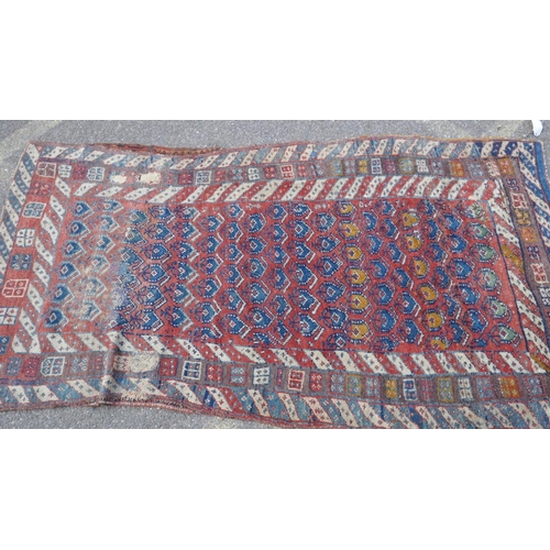 1030 - A Persian Shahsavan long wool rug, geometric designs on a terracotta field, 253 x 122cm, repaired