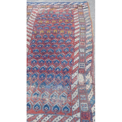 1030 - A Persian Shahsavan long wool rug, geometric designs on a terracotta field, 253 x 122cm, repaired