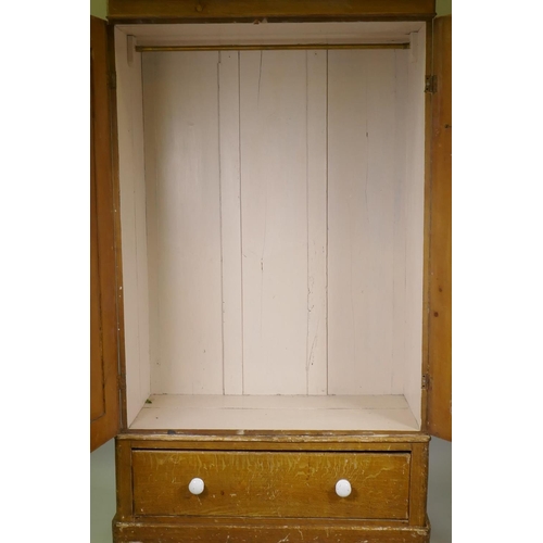 1033 - A Victorian grain painted pine wardrobe, with two doors over a single drawer, raised on a plinth bas... 