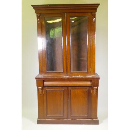 1040 - A Victorian mahogany bookcase in two sections, the upper with two glazed doors flanked by carved cor... 