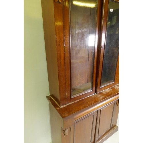 1040 - A Victorian mahogany bookcase in two sections, the upper with two glazed doors flanked by carved cor... 