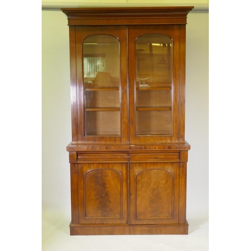 1083 - A Victorian mahogany bookcase with two arched glazed doors over two frieze drawers and cupboards, ra... 