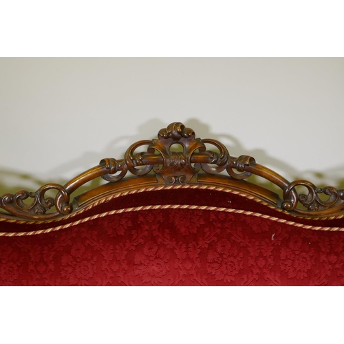 1092 - A Victorian showframe walnut two seater settee, with carved and pierced back scroll arms and shaped ... 