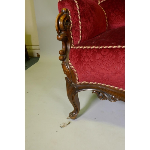 1092 - A Victorian showframe walnut two seater settee, with carved and pierced back scroll arms and shaped ... 