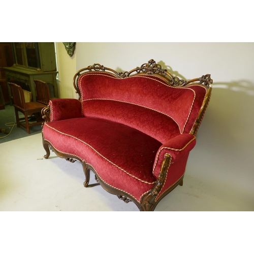 1092 - A Victorian showframe walnut two seater settee, with carved and pierced back scroll arms and shaped ... 