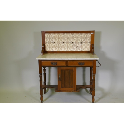 1099 - A Victorian walnut washstand with tiled back and marble top over two drawers and pot cupboard, raise... 