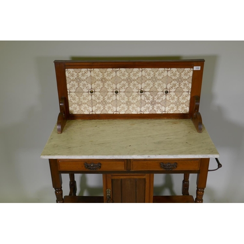 1099 - A Victorian walnut washstand with tiled back and marble top over two drawers and pot cupboard, raise... 