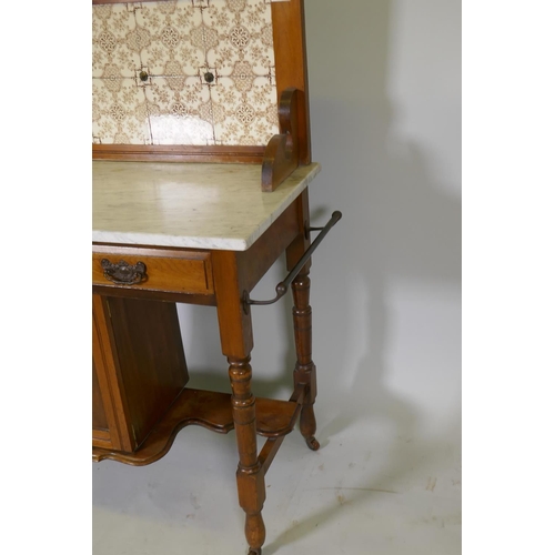 1099 - A Victorian walnut washstand with tiled back and marble top over two drawers and pot cupboard, raise... 