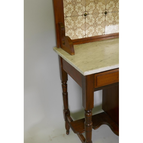 1099 - A Victorian walnut washstand with tiled back and marble top over two drawers and pot cupboard, raise... 