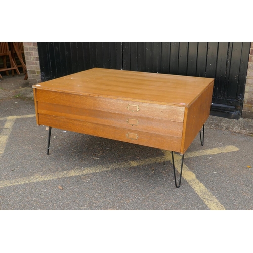 1142 - A mid century plan chest of three long drawers, raised on pin supports, 131 x 100 x 68cm