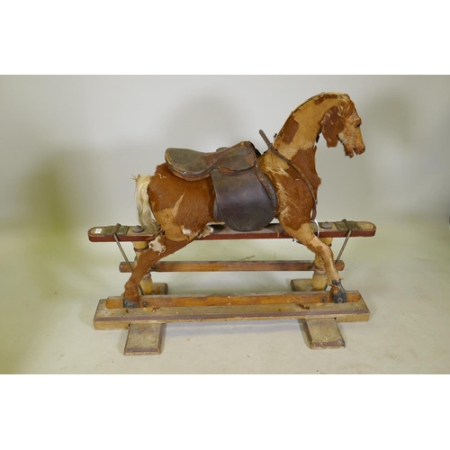 1158 - An antique rocking horse, stuffed straw and pony hide covers with leather saddle and painted pine ba... 