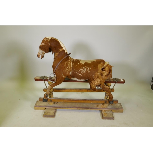 1158 - An antique rocking horse, stuffed straw and pony hide covers with leather saddle and painted pine ba... 