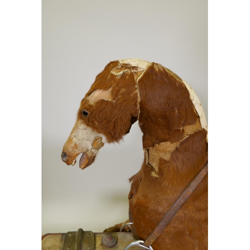 1158 - An antique rocking horse, stuffed straw and pony hide covers with leather saddle and painted pine ba... 