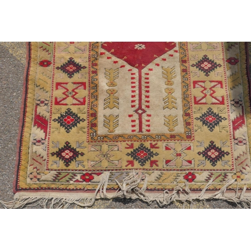 1225 - A Middle Eastern wool carpet with red central panel and gold coloured borders with geometric designs... 