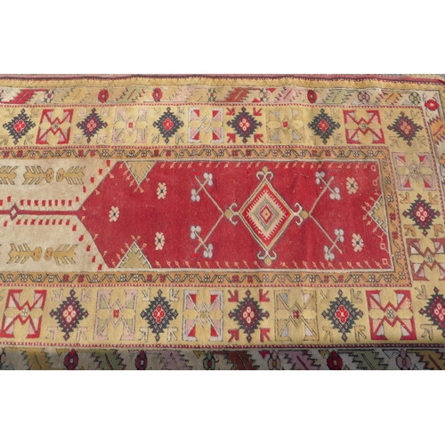 1225 - A Middle Eastern wool carpet with red central panel and gold coloured borders with geometric designs... 