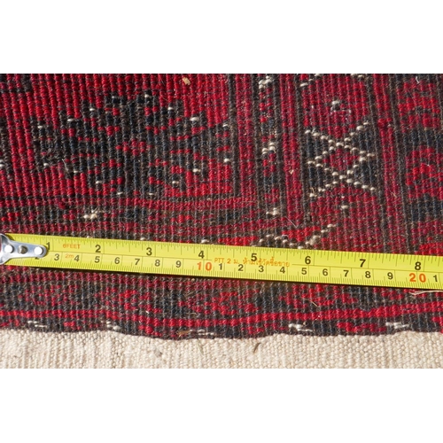 1226 - A vintage Bokhara wool rug with traditional design on a red field, 115 x 146cm