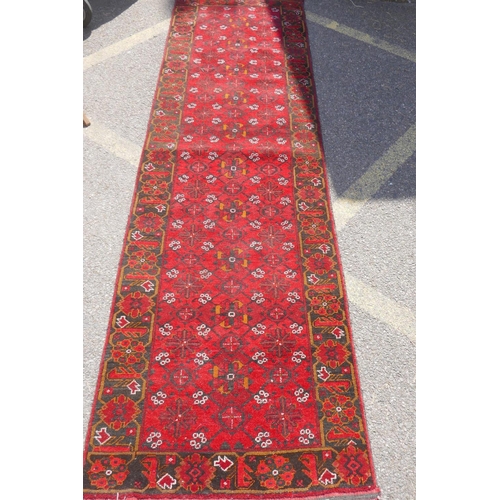 1227 - A Persian wool runner with geometric designs on a red field and black borders, 85 x 288cm