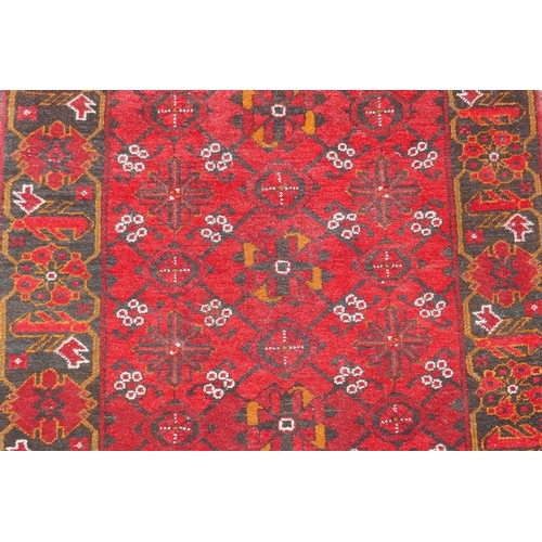 1227 - A Persian wool runner with geometric designs on a red field and black borders, 85 x 288cm