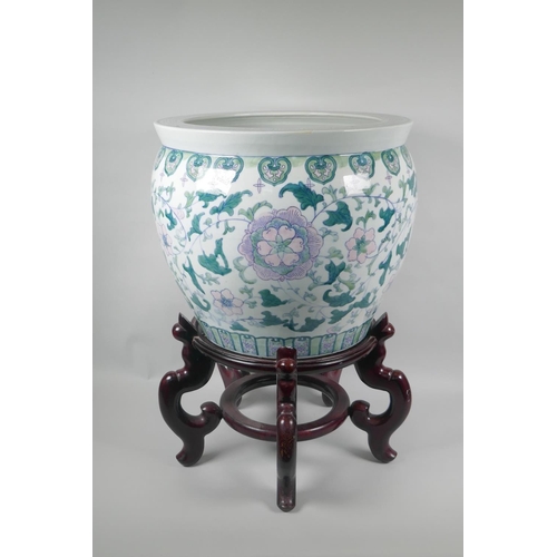 127 - A Chinese polychrome porcelain fish bowl with scrolling floral decoration, on a hardwood stand, stan... 