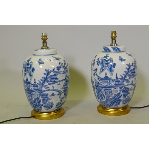 129 - A pair of oriental ceramic table lamps with typical blue and white decoration, mounted on giltwood b... 