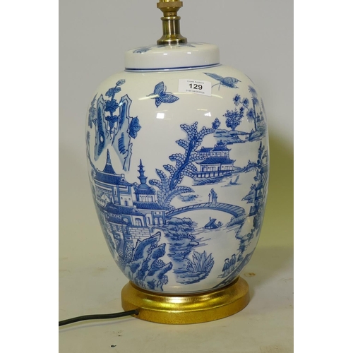 129 - A pair of oriental ceramic table lamps with typical blue and white decoration, mounted on giltwood b... 