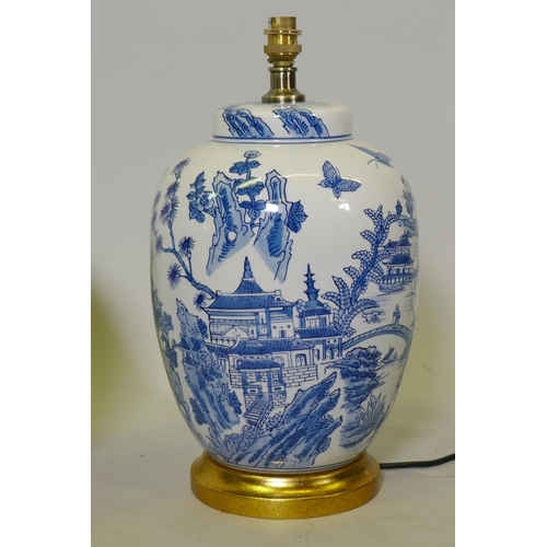 129 - A pair of oriental ceramic table lamps with typical blue and white decoration, mounted on giltwood b... 