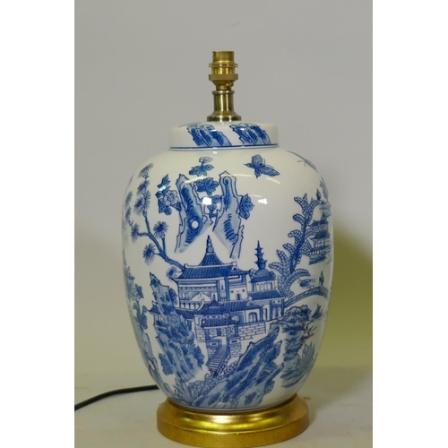 129 - A pair of oriental ceramic table lamps with typical blue and white decoration, mounted on giltwood b... 