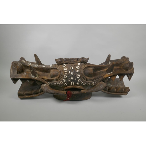 15 - An African Senufo Peoples carved hardwood Janus helmet mask (Wanyugo), inset with shells, 67cm long