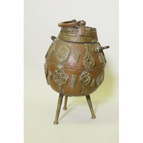 153 - Middle Eastern copper pot with applied brass decoration, raised on tripod supports, one detached, 50... 