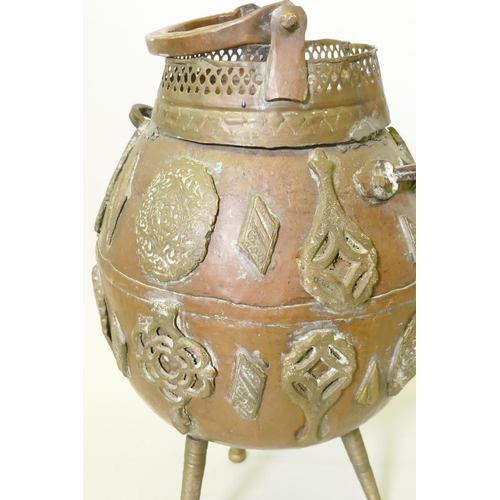 153 - Middle Eastern copper pot with applied brass decoration, raised on tripod supports, one detached, 50... 