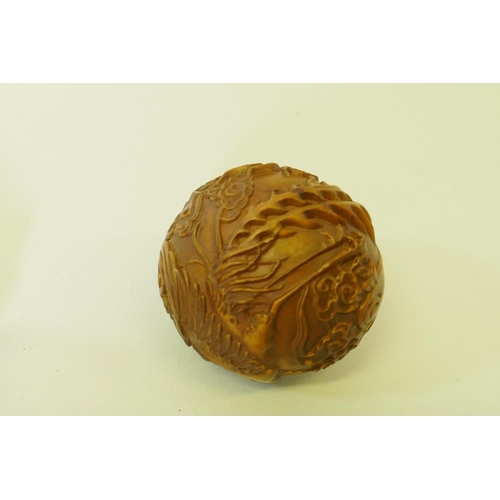 161 - A carved boxwood netsuke in the form of a foo lion, 5cm high, and a wood ball carved with a phoenix ... 