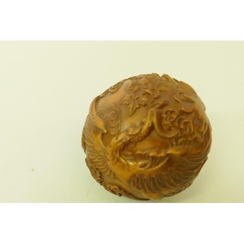 161 - A carved boxwood netsuke in the form of a foo lion, 5cm high, and a wood ball carved with a phoenix ... 