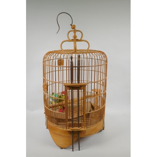 170 - An oriental bamboo bird cage, with famille verte porcelain bird feeder, 68cm high, 36cm diamete... 