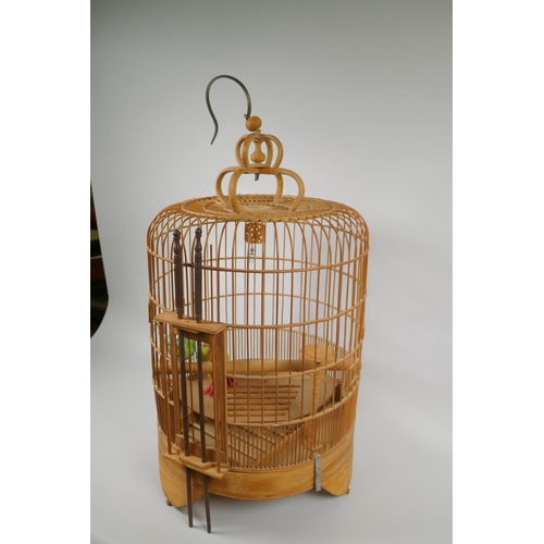 170 - An oriental bamboo bird cage, with famille verte porcelain bird feeder, 68cm high, 36cm diamete... 