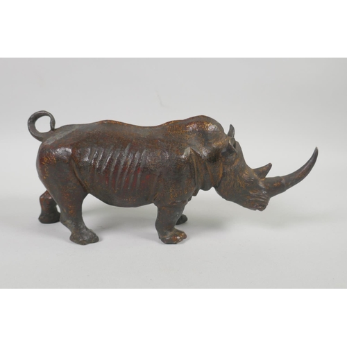 176 - A filled bronze figure of a rhinoceros with the remnants of gilt patina, 24cm long