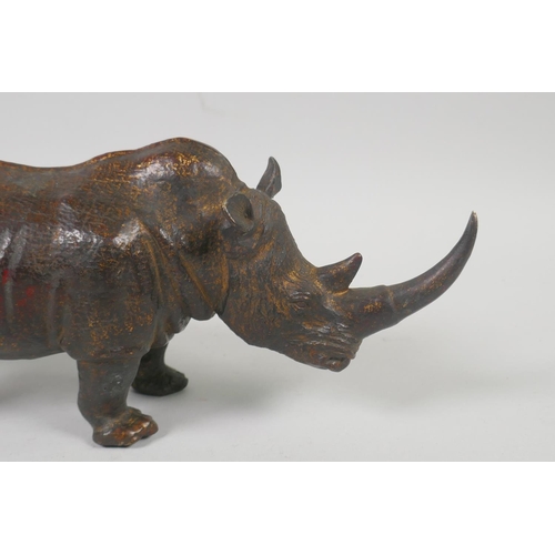 176 - A filled bronze figure of a rhinoceros with the remnants of gilt patina, 24cm long