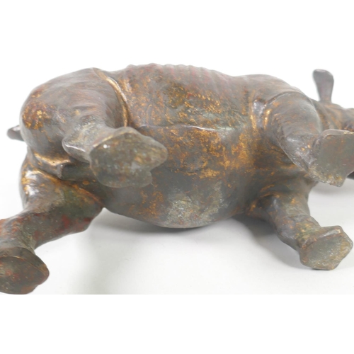 176 - A filled bronze figure of a rhinoceros with the remnants of gilt patina, 24cm long