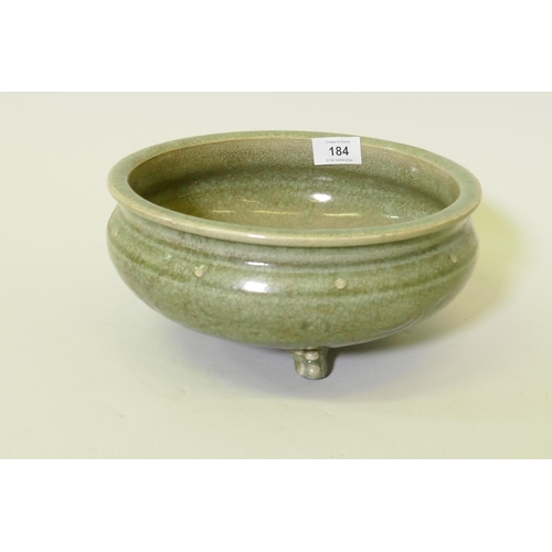 184 - An oriental crackle glazed green bowl with raised boss and low relief decoration, raised on tripod s... 